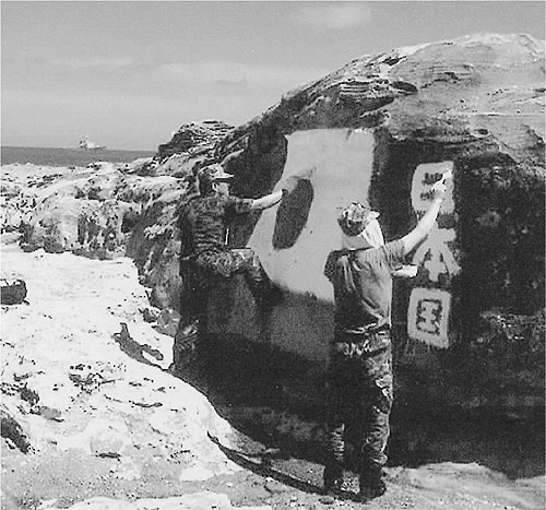 魚釣島の大岩に国旗を描く隊員
